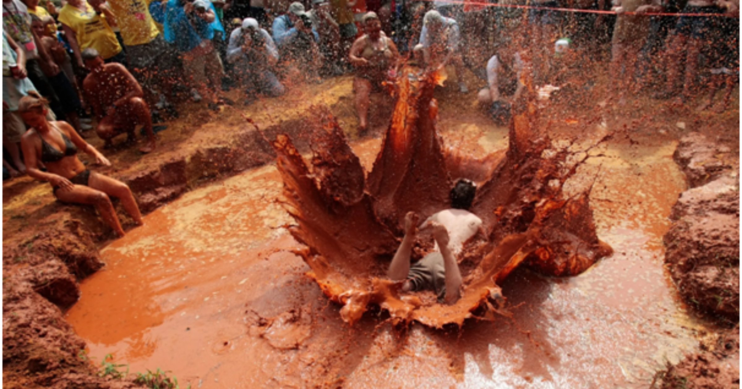 A red-clay spray showers spectators during a mud-pit belly flop at the Summer Redneck Games in Dublin, Georgia.